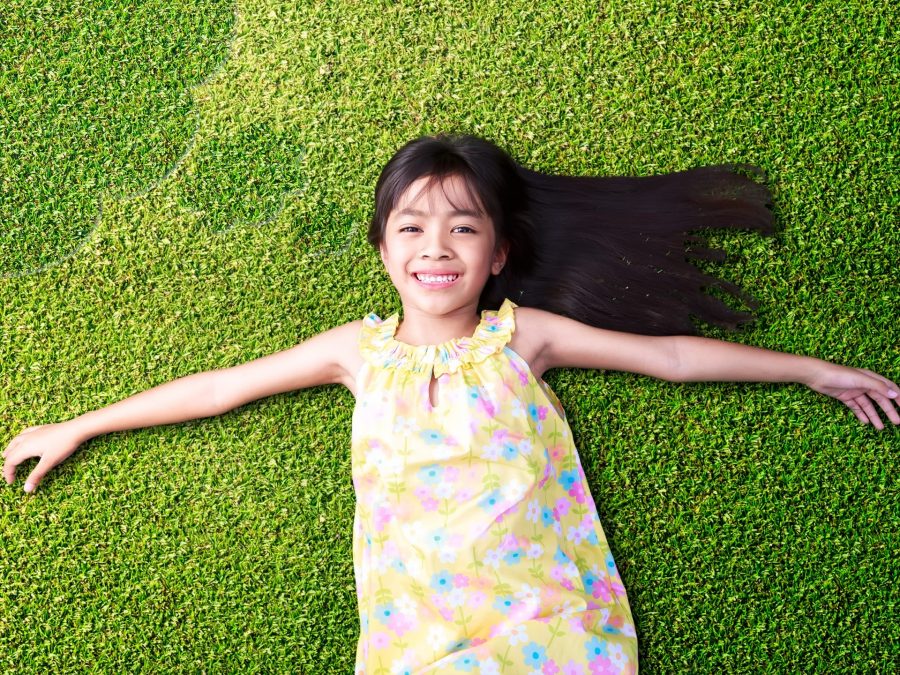 a smiling girl lying down on the grass