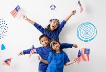 Three children, with smiles on their faces, holding out the Malaysian flag to celebrate Malaysia Human Rights.