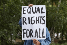 A young person holds up a sign that reads Equal Rights for All.